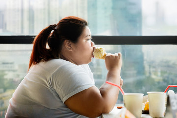 Young fat woman eating an ice cream in the cafe