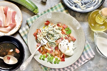 Low-Carb keto carbonara pasta with spaghetti (noodles) of zucchini with cream, fried bacon and poached egg. decorated with pea sprouts. in a beautiful light dish. top view