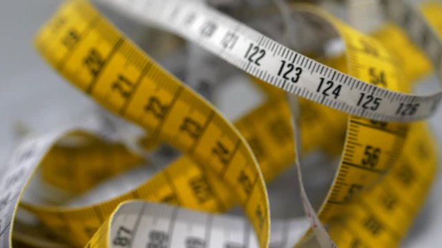 Closeup of rotating American and European measuring tapes, inches and centimeters, metric vs. imperial