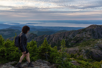 Adventurous girl hiking the beautiful trail in the Canadian Mountain Landscape during a vibrant summer sunset. Taken at Mt Arrowsmith, near Nanaimo, Vancouver Island, BC, Canada.