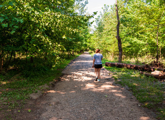 A girl walking along a dirt path in Frick Park, Pittsburgh, Pennsylvania, USA in summertime