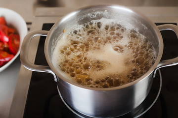 Boiling soup in pan on electric stove in the kitchen
