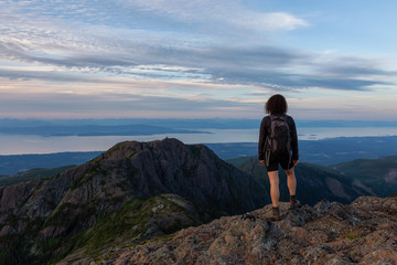 Adventurous girl hiking the beautiful trail in the Canadian Mountain Landscape during a vibrant summer sunset. Taken at Mt Arrowsmith, near Nanaimo, Vancouver Island, BC, Canada.