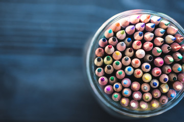 Colored pencils in a jar on a blue background