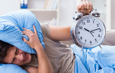 Man having trouble waking up with alarm clock