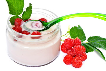 Pink cream or milk fruit yogurt with natural ripe red raspberry and leaves in open glass transparent jar with slim graceful spoon with berry next heap raspberry on white background close up. Isolated