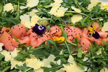 Abstract closeup of antipasti mixed event catering platter with smoked salmon, ceese and rocket