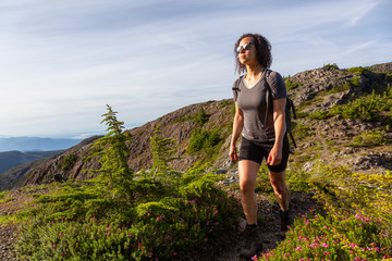 Naklejka premium Adventurous girl hiking the beautiful trail in the Canadian Mountain Landscape during a vibrant summer evening. Taken at Mt Arrowsmith, near Nanaimo, Vancouver Island, BC, Canada.