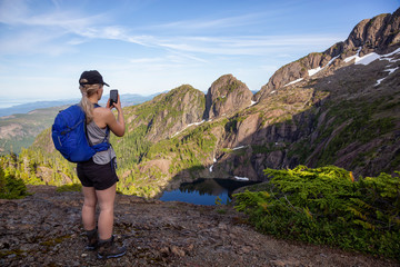 Fototapeta premium Adventurous girl hiking the beautiful trail in the Canadian Mountain Landscape during a vibrant summer evening. Taken at Mt Arrowsmith, near Nanaimo, Vancouver Island, BC, Canada.