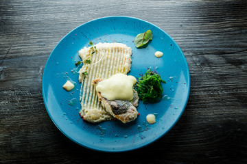 top view on baked white fish fillet with potato puree and sea kale
