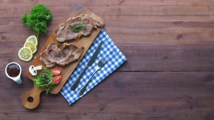 Grilled meat steak with barbecue sauce, tomatoes, basil, mushrooms and herbs on wooden board. Top view with copy space.