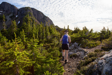 Adventurous girl hiking the beautiful trail in the Canadian Mountain Landscape during a vibrant summer evening. Taken at Mt Arrowsmith, near Nanaimo, Vancouver Island, BC, Canada.