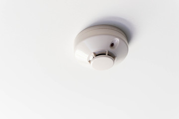 Close up of a smoke detector  attached on the ceiling of the hotel room, copy space