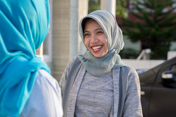 portrait of two neighboring hijab women were having a conversation in front of the house