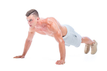 Sports man doing push ups isolated on a white background. Strong Athletic Man - Fitness Model showing his perfect body.