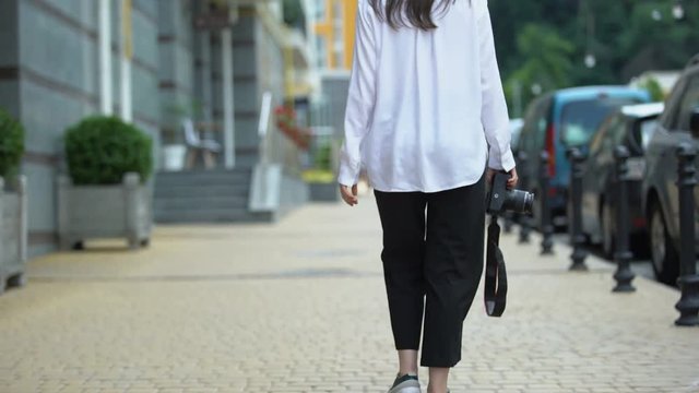 Female photographer walking with camera, searching for place to make photo