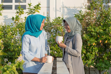 portrait of two hijab  women drinking tea in front of the house and talking