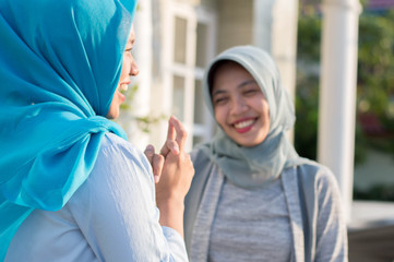 Fototapeta premium portrait of two neighboring hijab women were having a conversation in front of the house