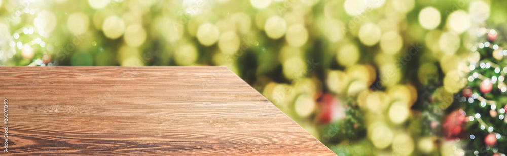 Poster Perspective wood table with blur Christmas tree decorate string light  background green bokeh light.Panoramic wooden countertop banner mock up for product display greeting card design online content.