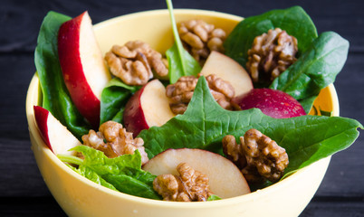 Spinach salad with nuts and apples served on table