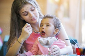 Cute black baby girl with mom in a summer cafe.