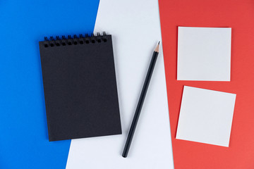 Blacklist France. Mourning, ban, sanctions, politics. black notebook, pencil and two notes lies on French flag. Mock up, copy space, pattern, cardboard texture.