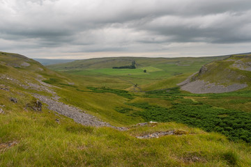 Fototapeta na wymiar Moughton Scar is a vast and impressive limestone pavement full of interesting nooks and crannies. In the distance a moody Pen-y-ghent is seen in profile.