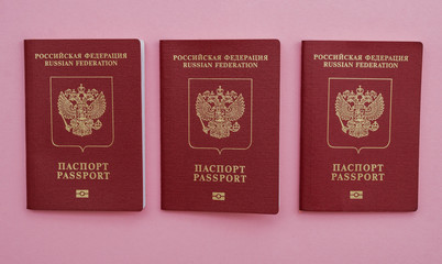 three Russian international passports on a pink background