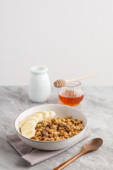 Breakfast with granola with banana. Jar of honey on background