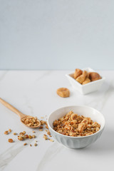 Two wooden bowls of granola on white marble table