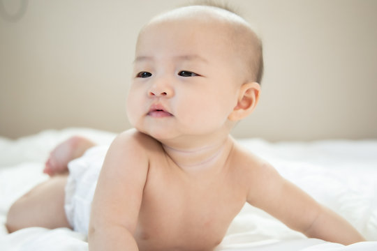 Asian baby happy in the room.Asian baby girl lying down on bed .