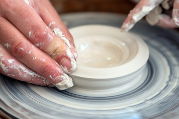 Potter makes pottery dishes on potter's wheel