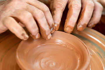 Potter makes pottery dishes on potter's wheel