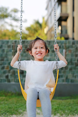 Happy cute little girl on swing in the park