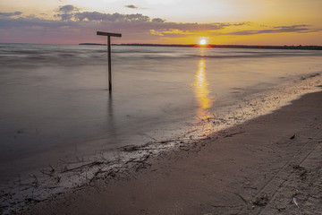 sunset at Sandbanks Beach Picton Ontario Canada with nice sun, clouds, branches, lake view, sand, and light.