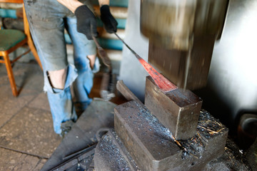 Blacksmith forging by using pneumatic hammer.