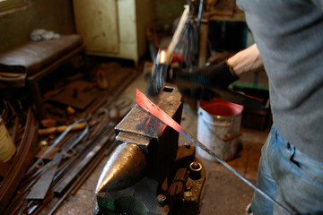 Blacksmith forging red-hot metal with hammer.