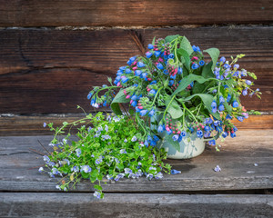 Bouquet of wild flowers in an enamel mug on the porch of a village house