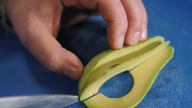 Close up of chef male hands cooking with avocado at table slice knife cut macro
