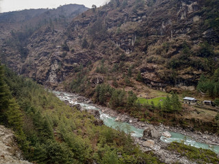 Dudh Koshi snow river (Dudh Kosi river or Milk-Koshi River) flows in mountain valley near Phakding village in Himalayas in Nepal. Nature, Lakes and Rivers, Mountains, Travel and Tourism concept. - obrazy, fototapety, plakaty