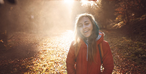 woman hiker with backpack wearing in red jacket is walking through a foggy autumn woods at the...
