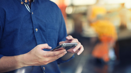 Cropped shot photo of man's hands using smartphone with outdoor background.