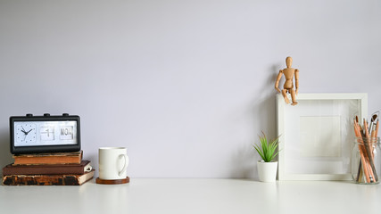Obraz na płótnie Canvas Workspace photo frame, coffee, alarm, books with plant decorate on white table.