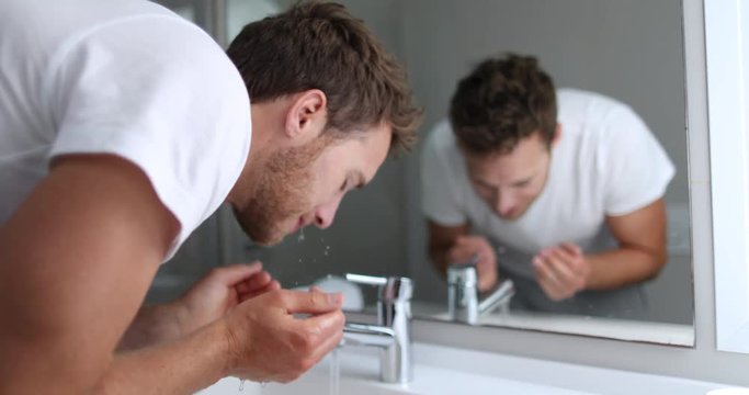 Man washing face rinsing soap from skin in sink under running cold water from faucet, Morning skincare routine. Male beauty skin care facial wash. Mask treatment. 4K (UHD) 59.94 FPS SLOW MOTION.