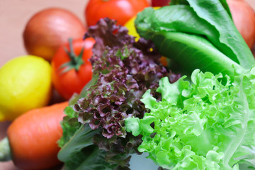 Mixed Fresh colorful vegetables On the wood floor  include tomato garlic lemon  lime  onion  red onion carrot Green Cos Lettuce Green oak  close up soft focus