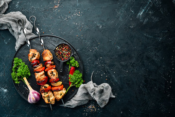 Chicken shish kebab with onions and tomatoes. Barbecue. On a black background. Top view. Free space...