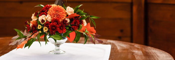 autumn floral bouquet in a pumpkin vase for Halloween. Table setting for wedding