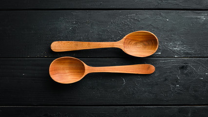 A wooden spoon on a black background. Top view. Free space for your text.
