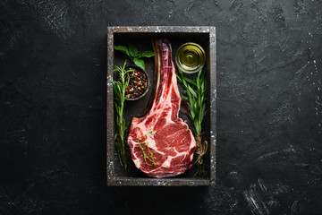 Raw dry steak tomahawk on a black background. Steak Cowboy. Barbecue. Top view. Free space for text.