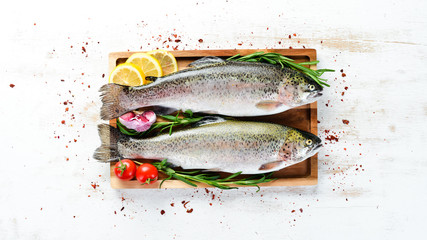Raw fish with vegetables on a white wooden background. Fish trout. Top view. Free space for your text.